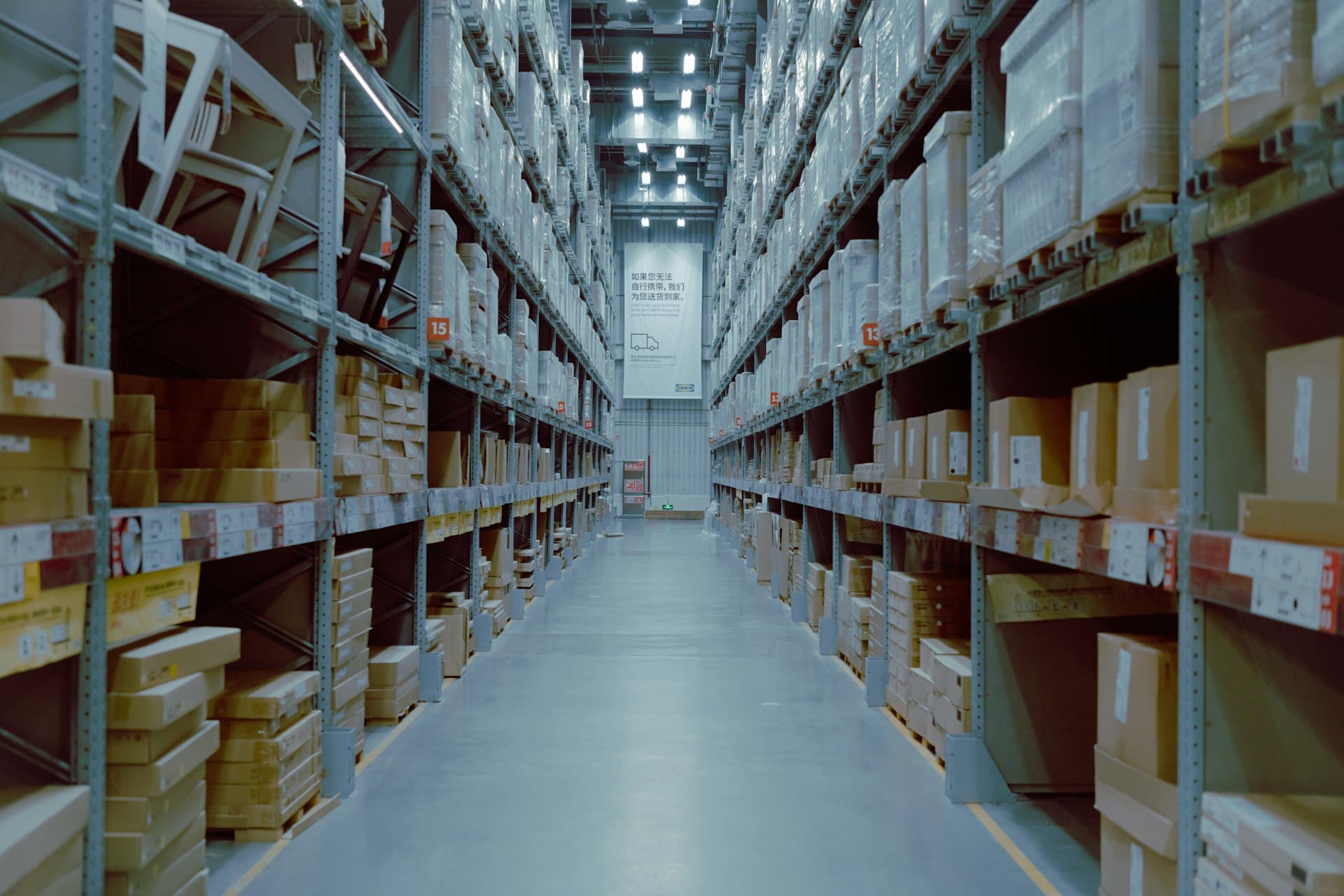 Long center aisle of a modern logistics warehouse flanked by tall racks stacked with boxed inventory