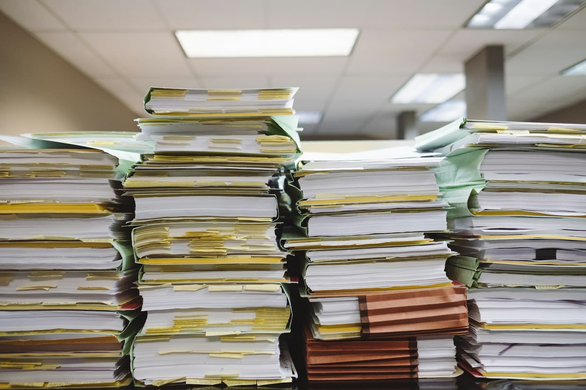 Tall stacks of paper documents and tabbed file folders in an office
