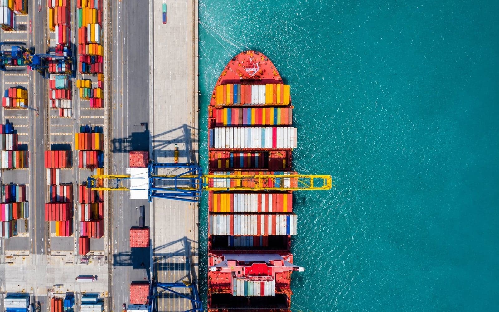 Aerial view of a busy container port with cranes and stacked containers