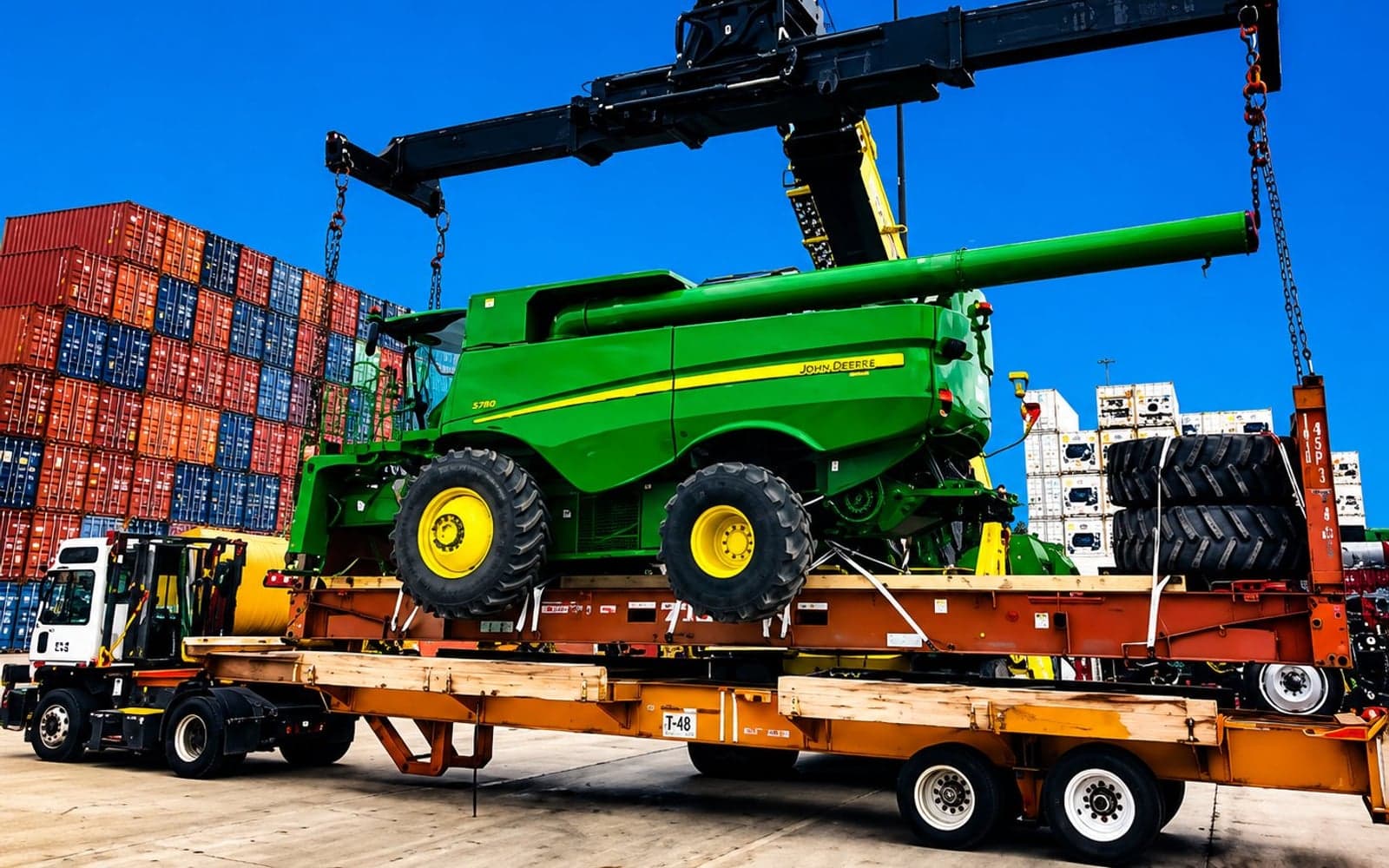 Large combine harvester being craned onto a flatbed trailer