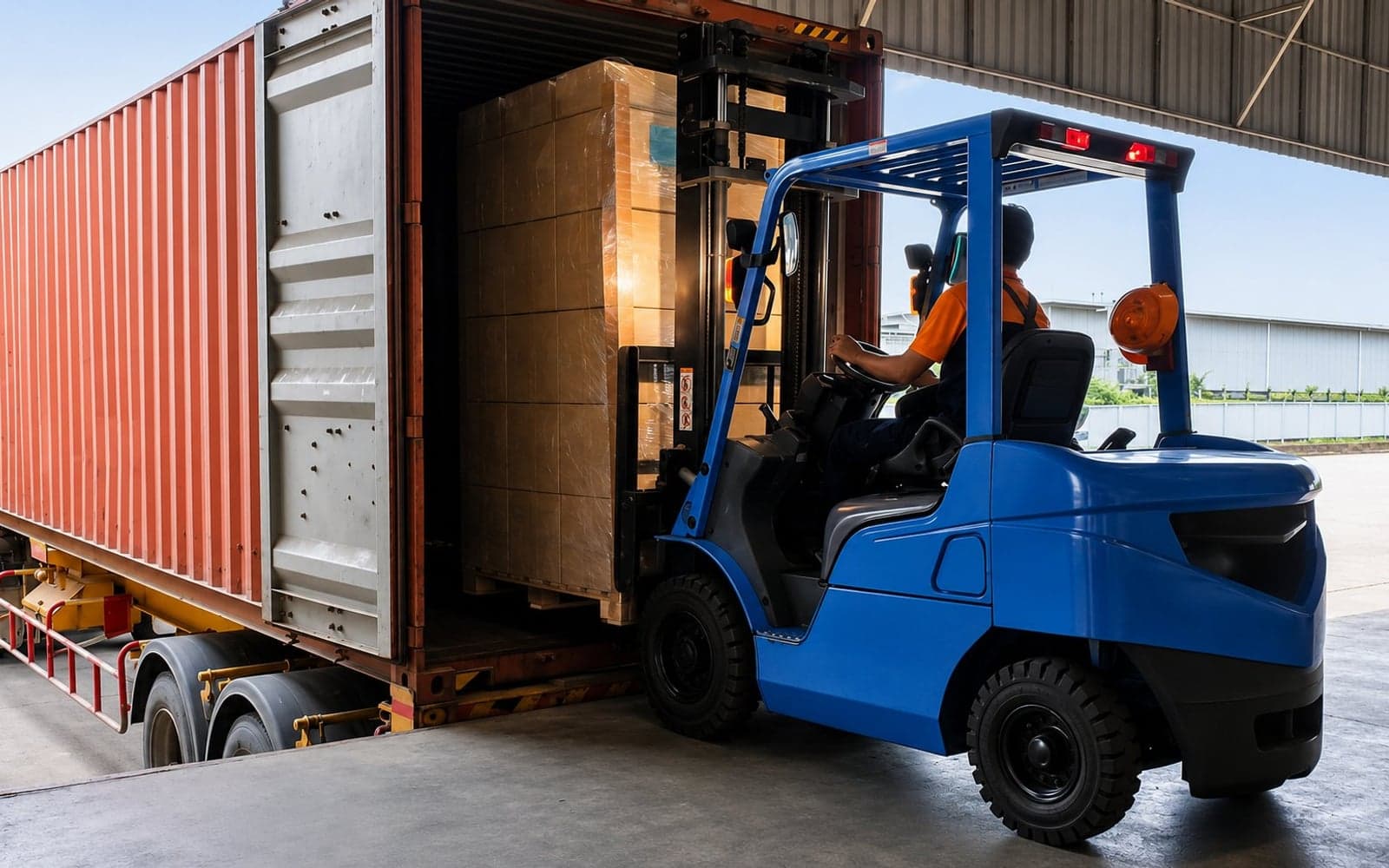 Forklift loading a shipping container inside a warehouse